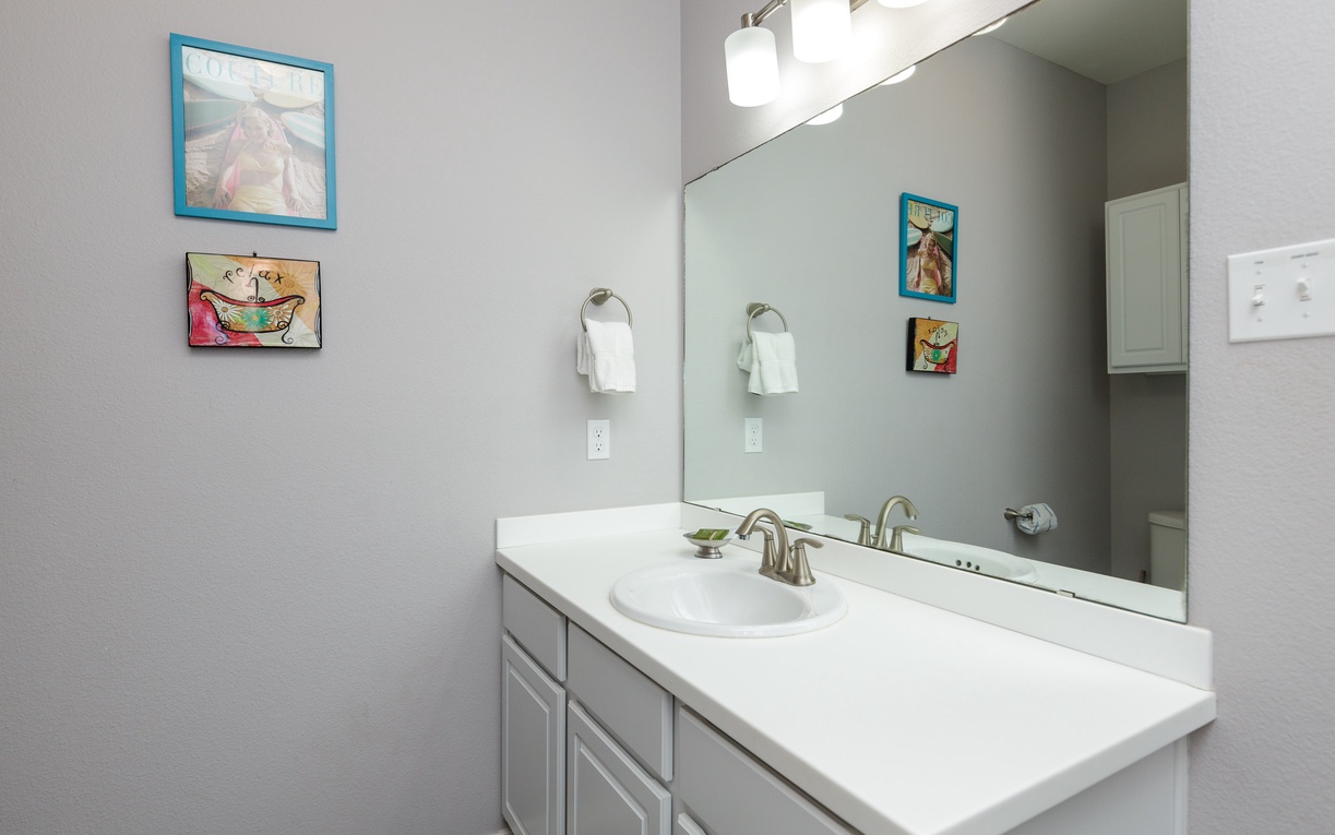 Freshen up in your private bathroom featuring clean lines, bright vanity lighting, and charming artwork that adds personality to your morning routine.