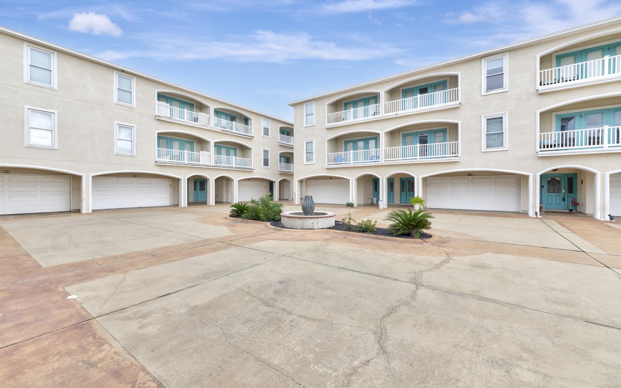 Modern beachside complex with spacious units featuring private garages and coastal-inspired architecture under sunny skies.