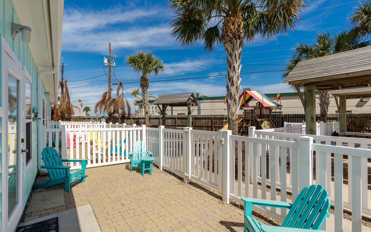 Your private patio beckons with turquoise Adirondack chairs and tropical palms swaying overhead—perfect for morning coffee or sunset cocktails.