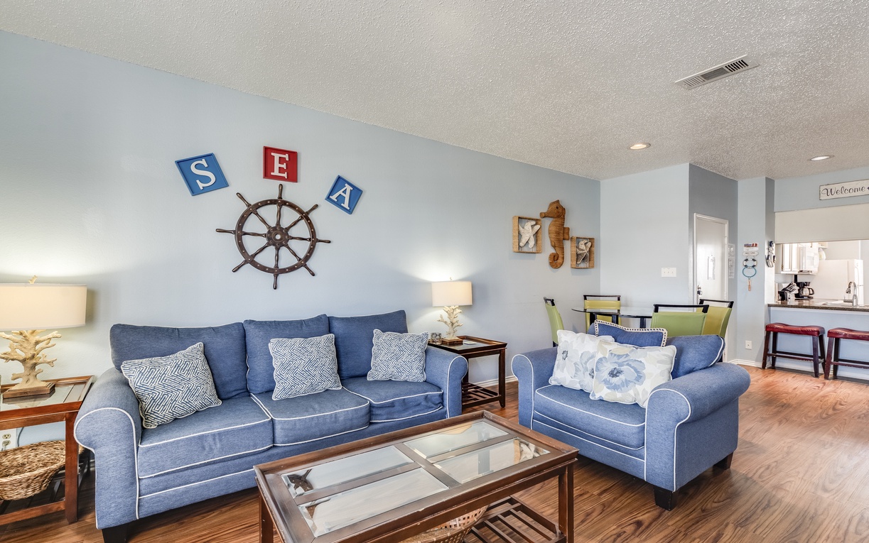 Your coastal-themed living room features comfortable blue furniture and charming nautical decor, creating the perfect seaside retreat atmosphere.