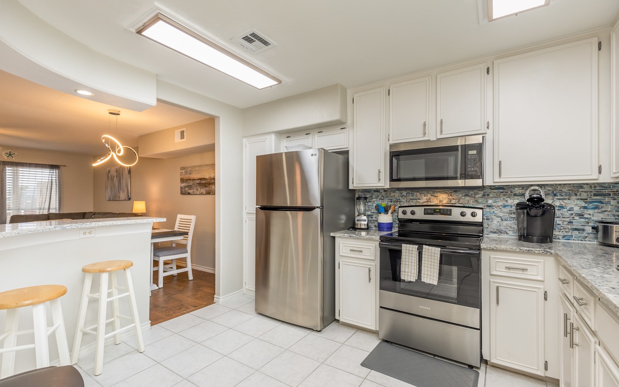 Your bright, modern kitchen awaits with stainless steel appliances, granite counters, and stylish backsplash—perfect for whipping up morning coffee.