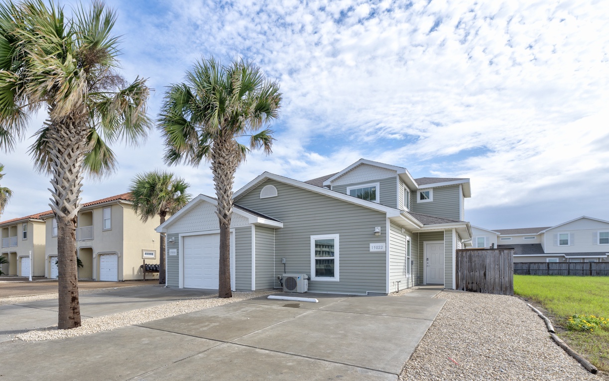 Modern coastal home with tropical palm trees and convenient parking in a peaceful beachside neighborhood setting.