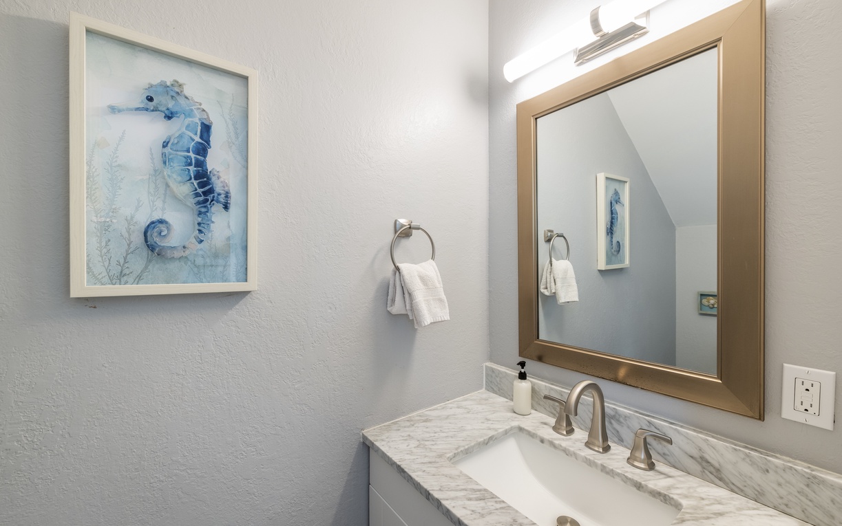Your beautifully appointed bathroom features elegant marble countertops and coastal-themed artwork, creating a serene space to refresh and unwind after your adventures.