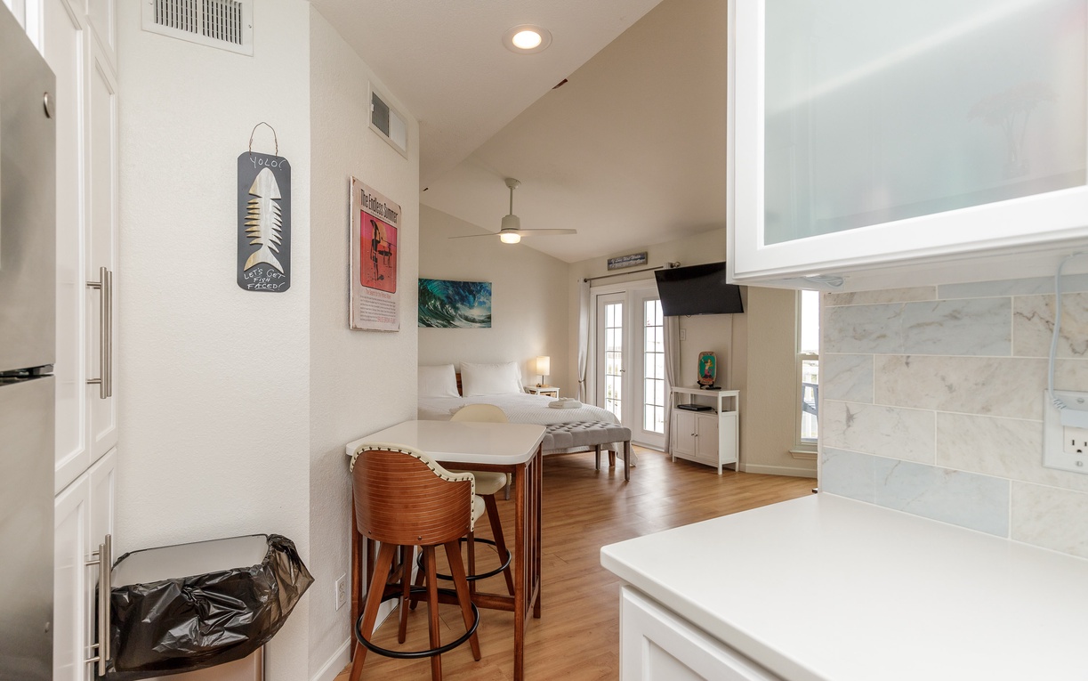 Your bright, open studio welcomes you with gleaming hardwood floors, coastal artwork, and a breakfast bar perfect for morning coffee.