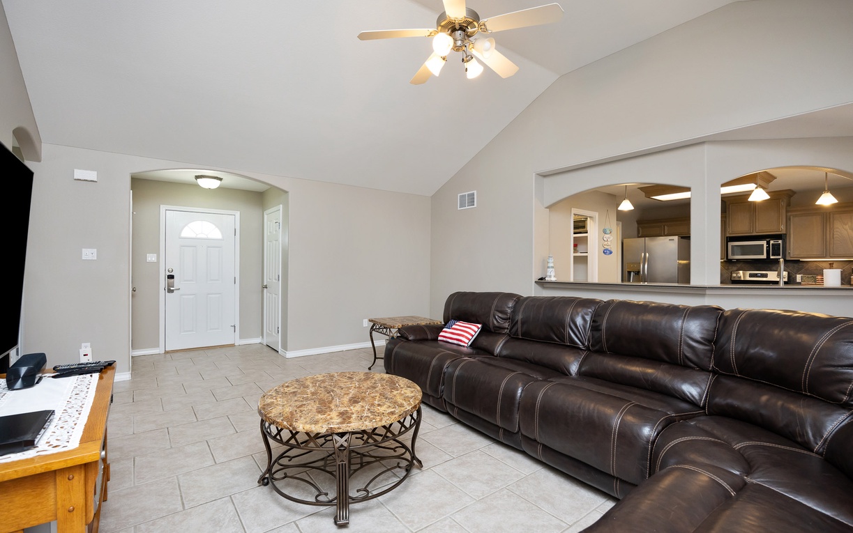 Relax in your spacious living room with plush leather seating, vaulted ceilings, and an open view to the modern kitchen.