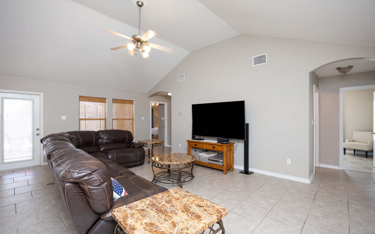 Relax in this spacious living room with comfortable leather seating, entertainment center, and vaulted ceilings that create an airy, welcoming atmosphere.