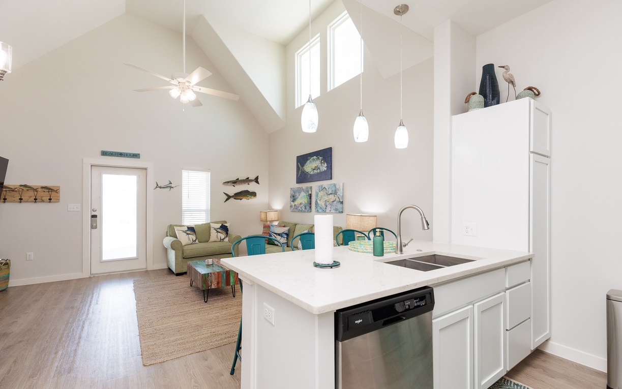 Your open-concept kitchen flows seamlessly into the living area, with vaulted ceilings and coastal-themed decor creating a bright, airy retreat.