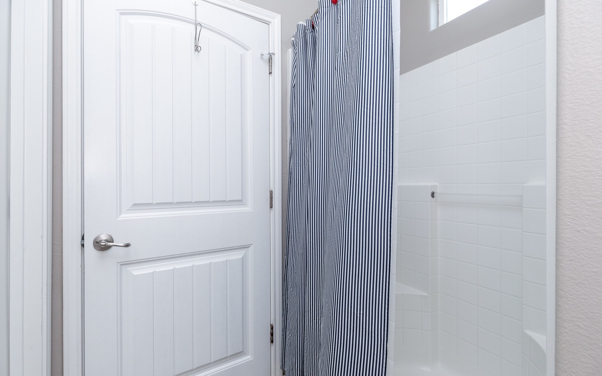 Step into your fresh, clean bathroom featuring a spacious shower with classic blue-striped curtain and crisp white surroundings.