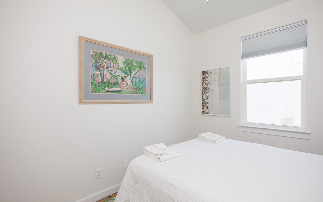 Drift off to sleep in this peaceful bedroom with crisp white linens and cheerful artwork creating your perfect retreat.