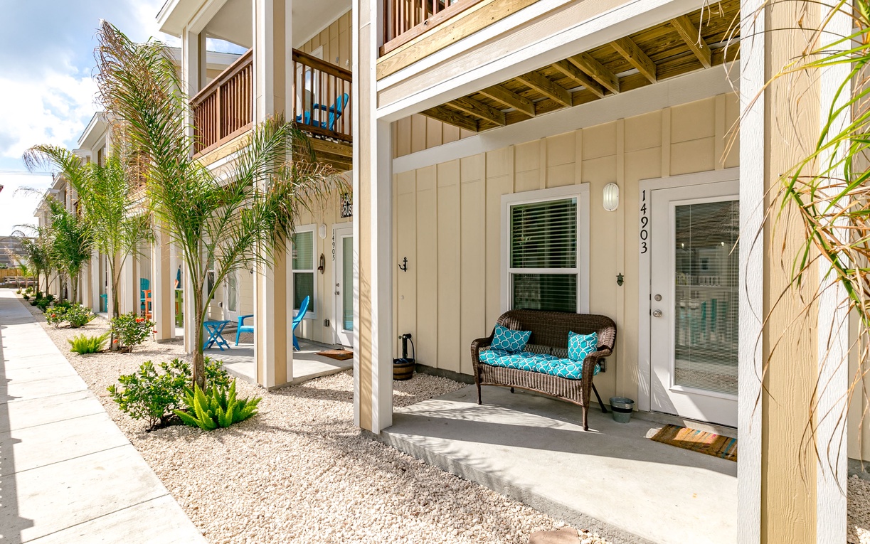 Modern coastal property featuring tropical landscaping and convenient ground-floor entrance with covered seating area.