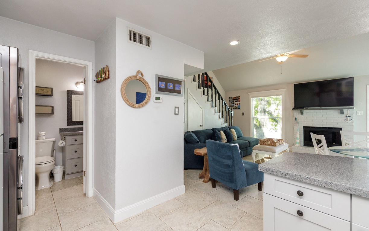 Relax in your open-concept living space with plush blue seating, cozy fireplace, and modern kitchen—perfect for unwinding after exploring.