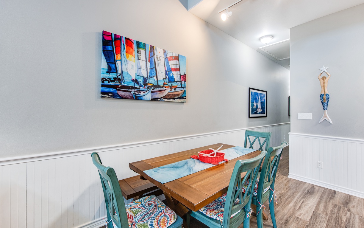 Your coastal-themed dining room features charming nautical artwork and cheerful turquoise chairs, creating the perfect spot for memorable meals together.