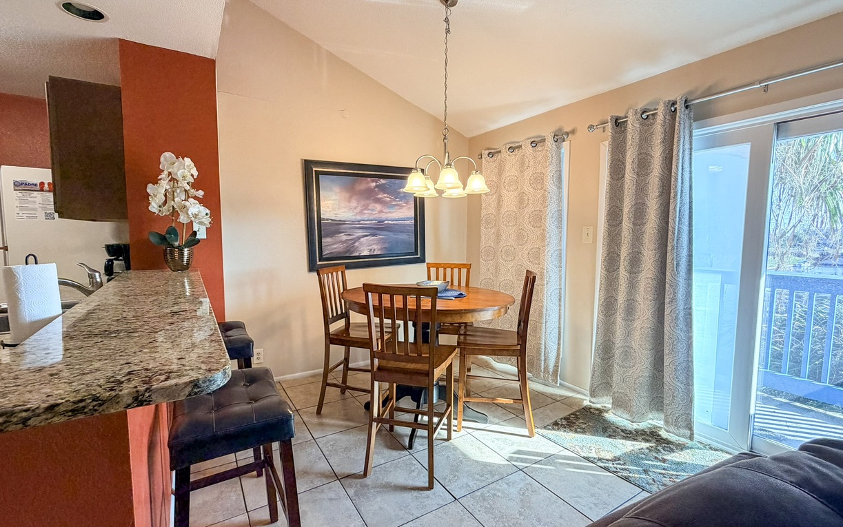 Your open-plan dining and kitchen area flows seamlessly together, with granite countertops and a cozy dining table perfect for shared meals.