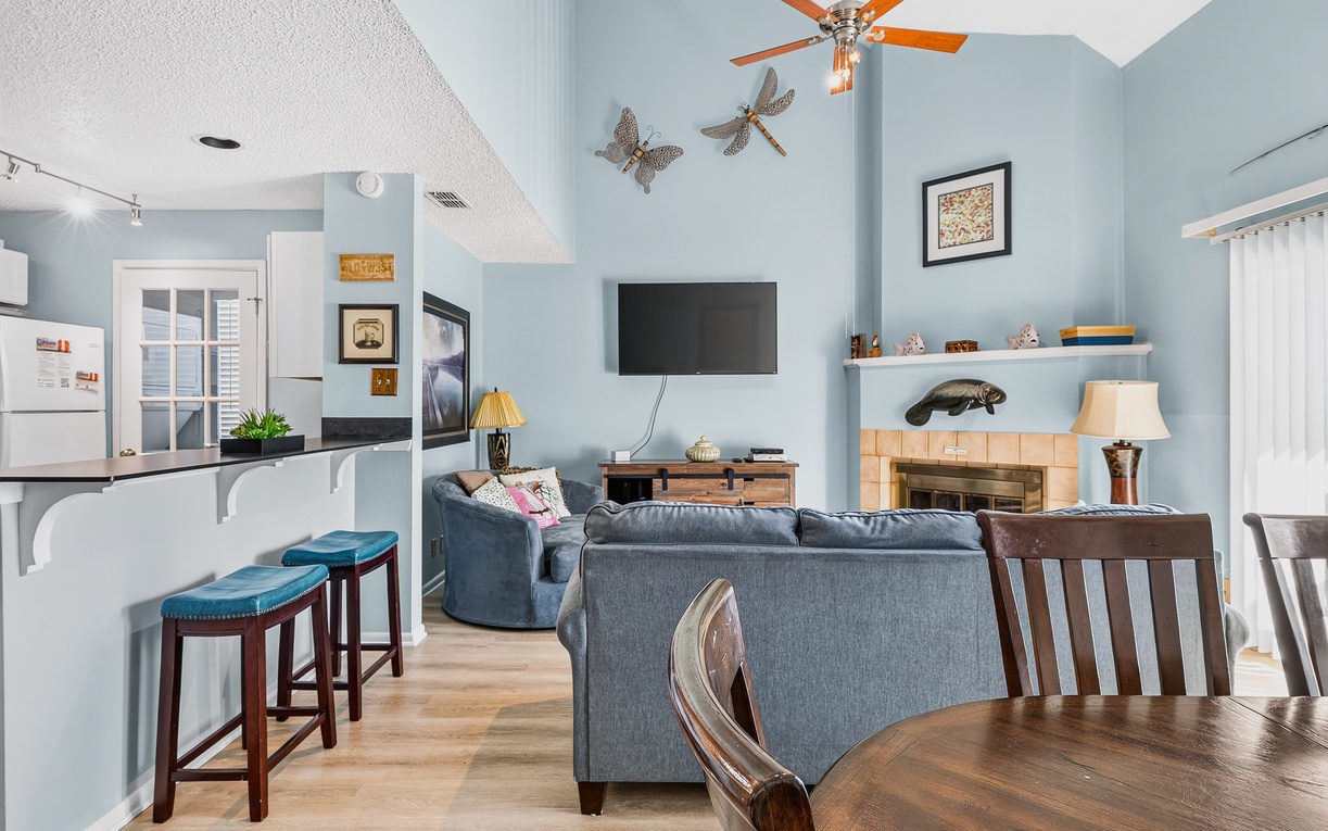 Settle into your airy retreat, where vaulted ceilings and coastal charm greet you. Unwind on the plush sofa, catch your favorite show, or gather around the dining table—your home away from home awaits.
