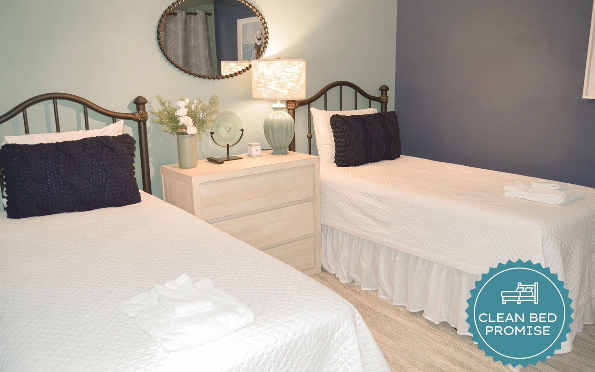 Unwind in your peaceful twin bedroom featuring crisp white linens, soft lighting, and thoughtful touches like fresh flowers.