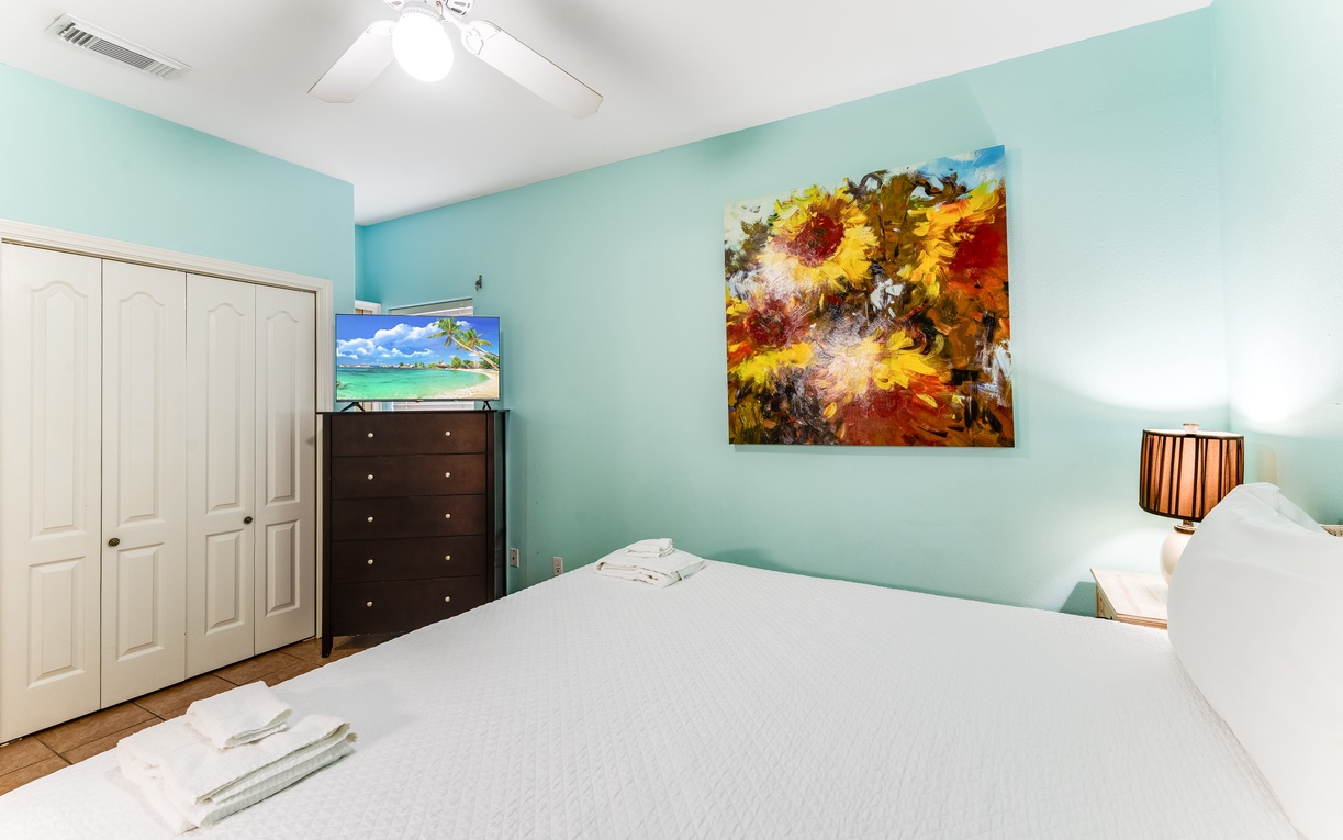 Drift off in your peaceful bedroom with calming turquoise walls, comfy bedding, and cheerful sunflower art creating the perfect retreat.