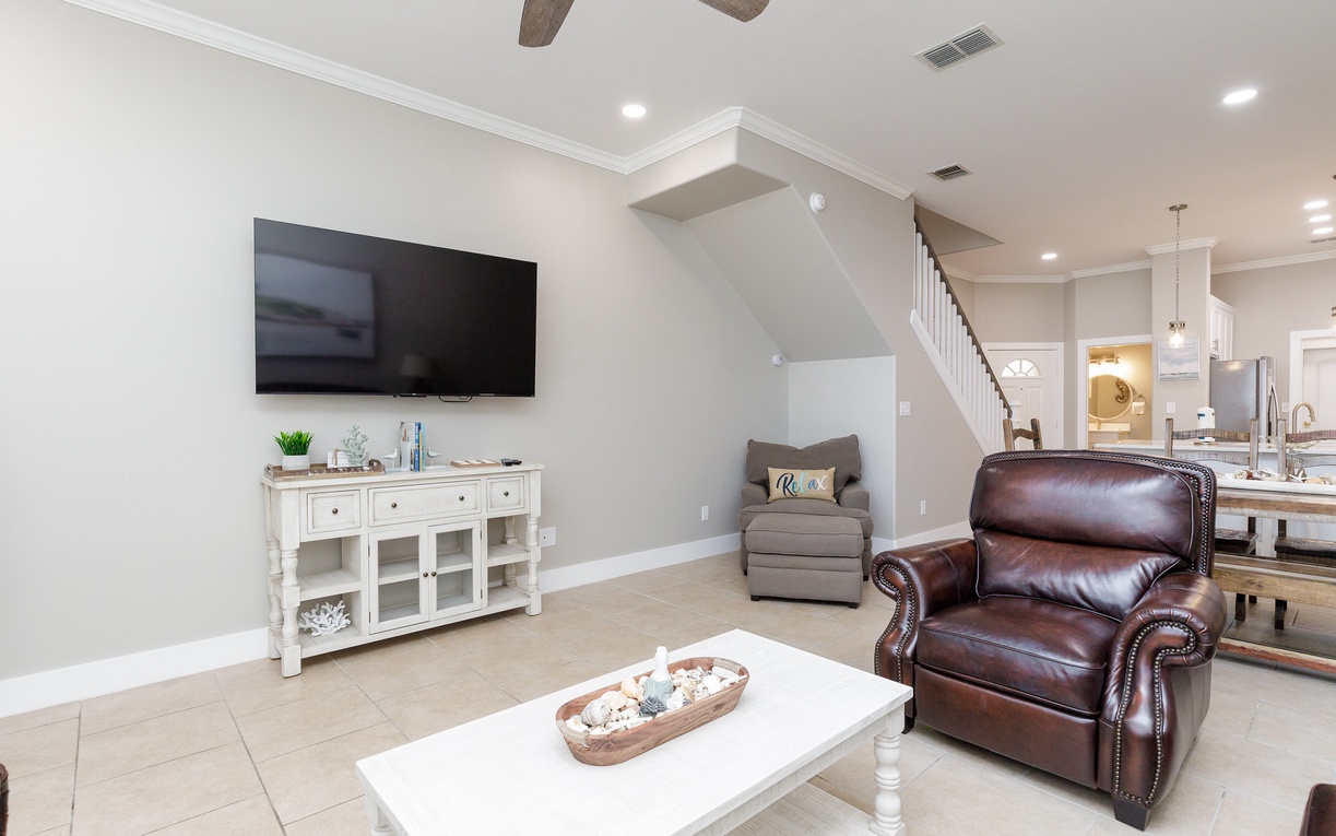 Relax in your elegant living room with soaring ceilings, rich leather seating, and modern entertainment center perfectly positioned for cozy evenings.