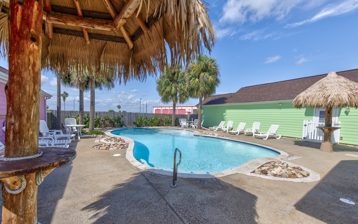 Dive into your own tropical paradise with this sparkling kidney-shaped pool, complete with tiki-style cabana and lounge chairs for ultimate relaxation.