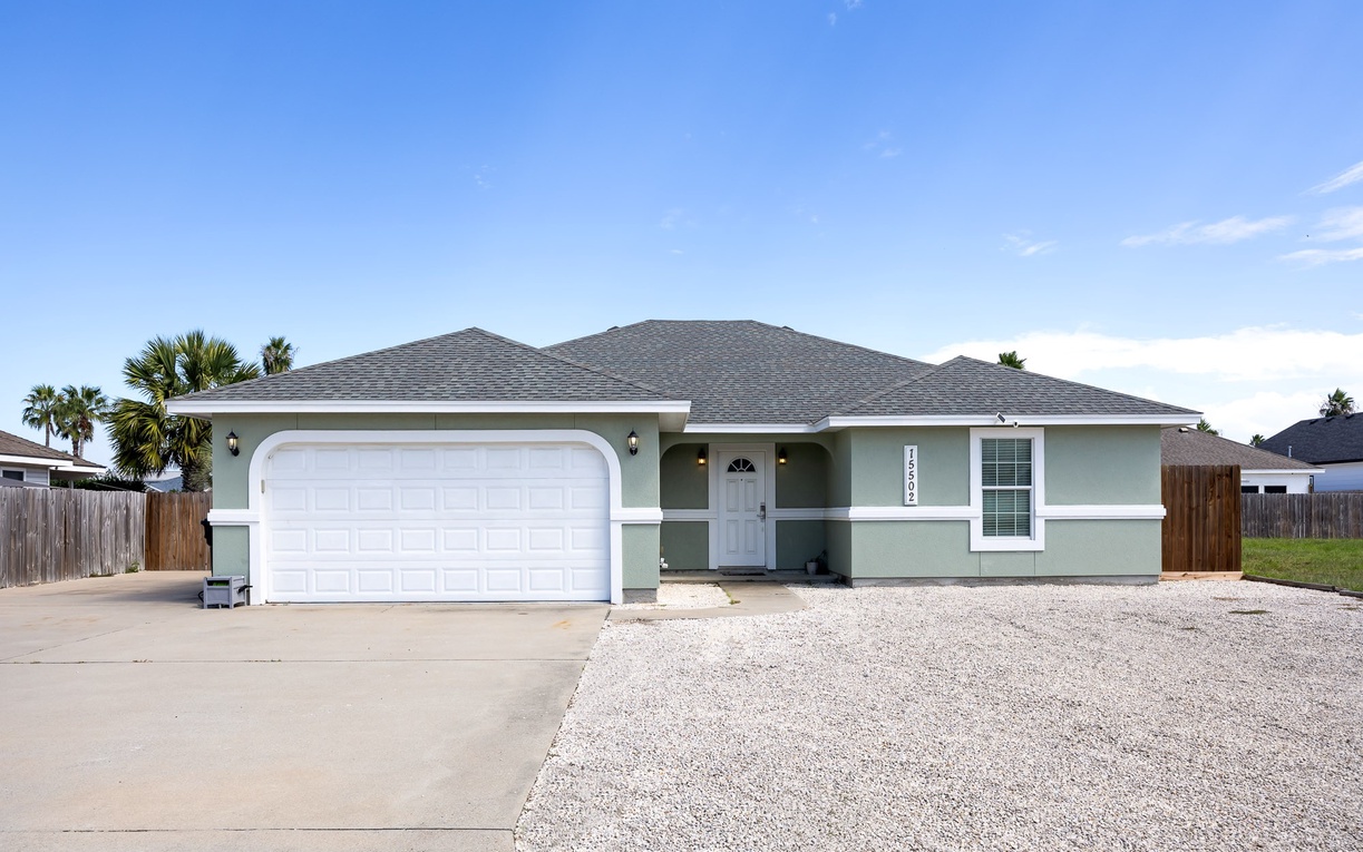 A charming single-story home with spacious driveway and tropical palms creates your perfect coastal getaway backdrop.