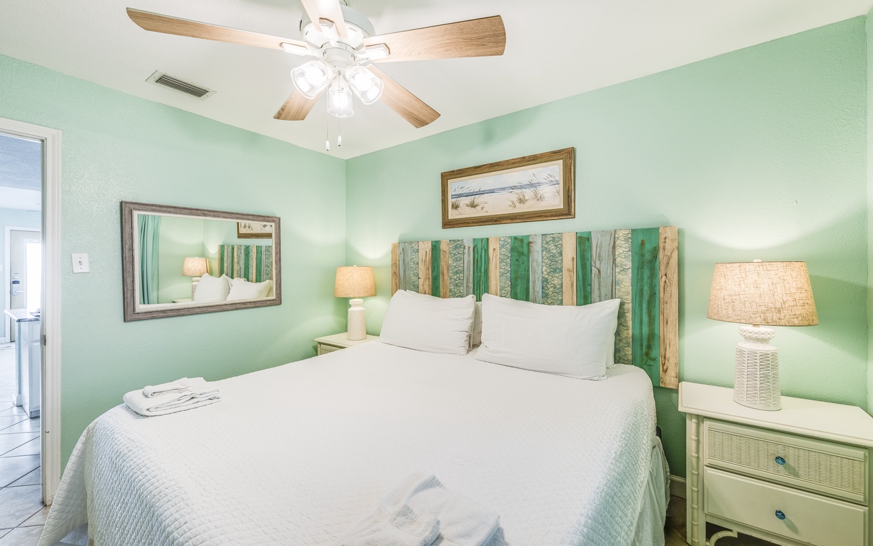 Rest peacefully in your coastal-inspired bedroom with soothing mint walls, rustic wood headboard, and gentle ceiling fan breeze overhead.