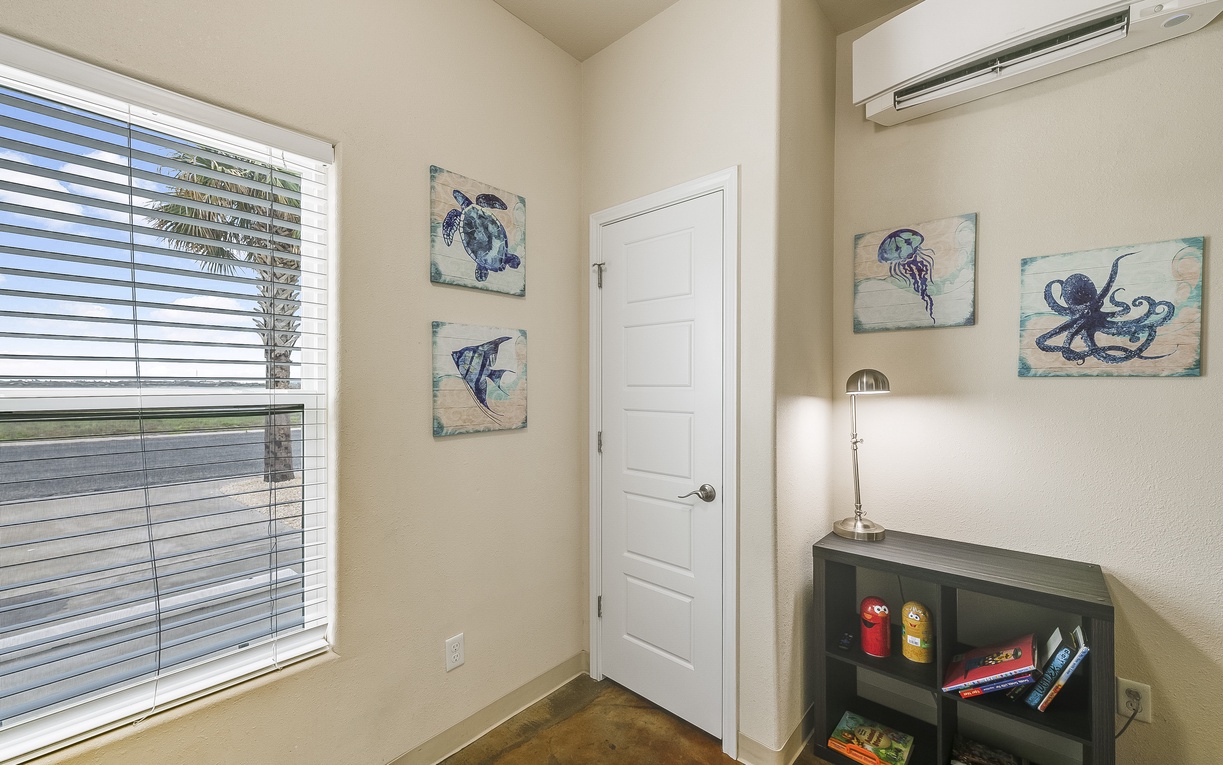 Your cozy reading nook awaits with nautical artwork, natural light, and a bookshelf stocked with vacation reads.
