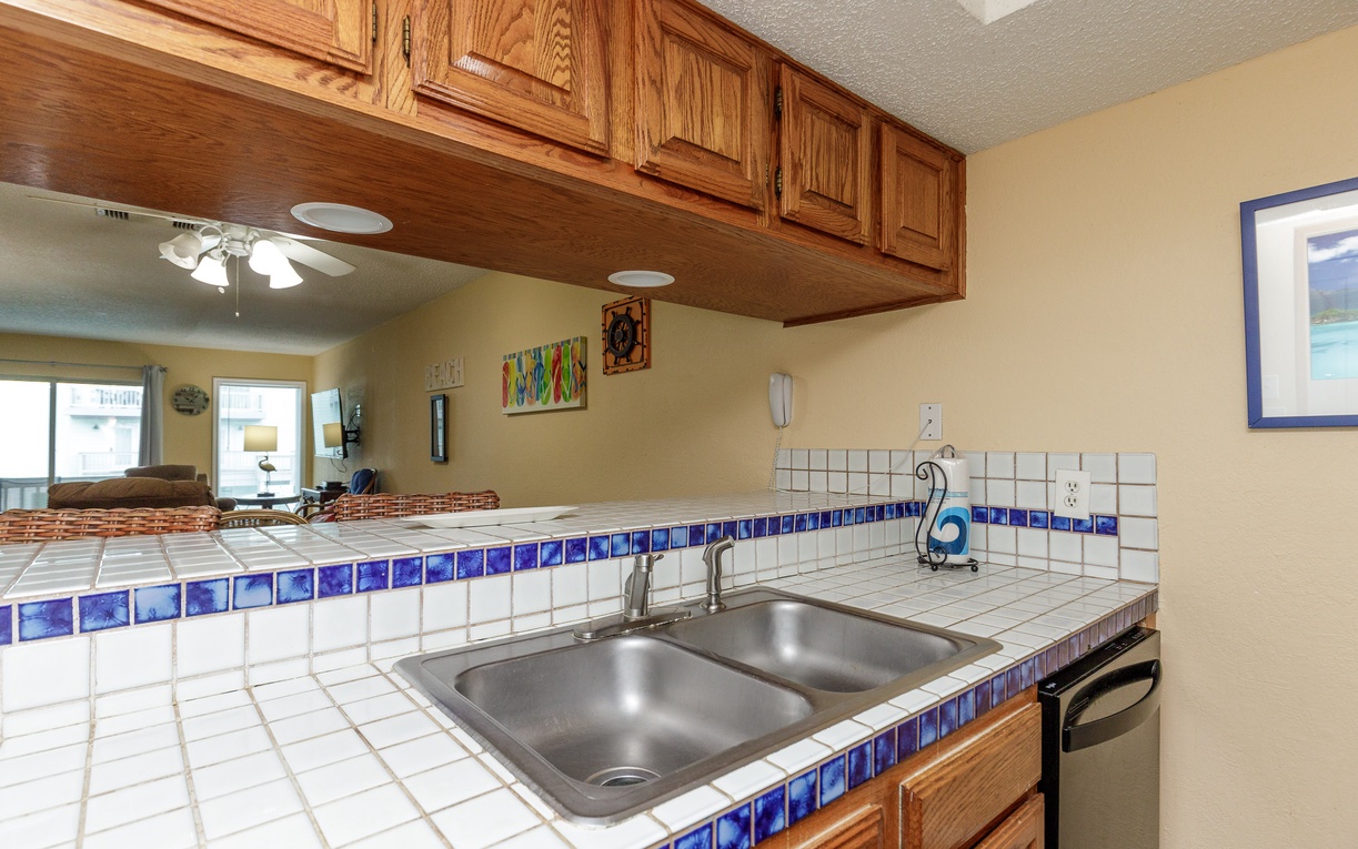Your kitchen features warm wood cabinets and charming blue tile accents, perfect for preparing meals with a view of the living area.
