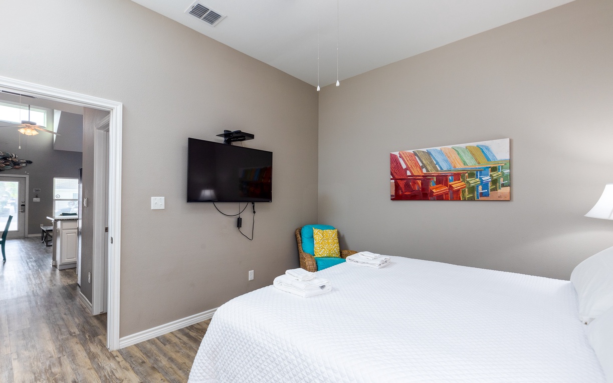Sink into crisp white linens and unwind with your favorite shows on the wall-mounted TV in this serene bedroom retreat.