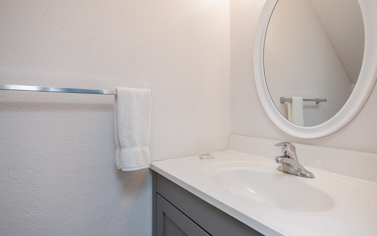 Fresh towels await your arrival in this pristine bathroom with modern fixtures and elegant round mirror for your daily routines.