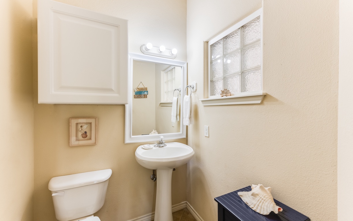 Step into your bright, well-appointed powder room featuring a classic pedestal sink and thoughtful coastal touches that make freshening up feel special.