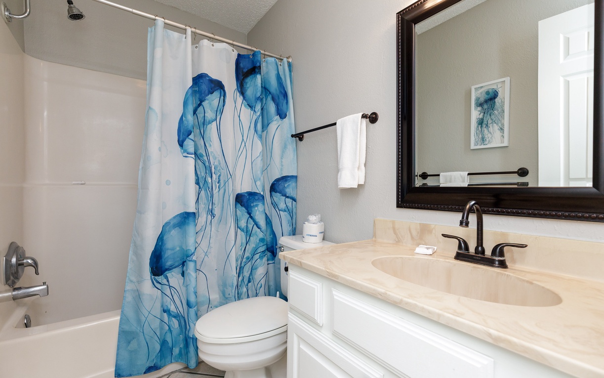 Step into your serene bathroom featuring ocean-inspired artwork and a pristine shower-tub combo, creating your perfect refreshing retreat.