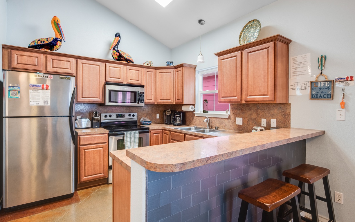 Your fully equipped kitchen invites culinary adventures with warm wood cabinets, stainless steel appliances, and a welcoming breakfast bar for morning coffee.