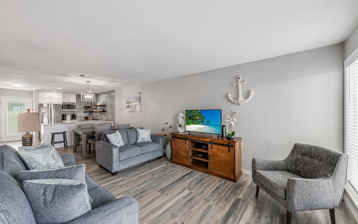 Sink into plush gray sofas in your open-concept living space, where coastal charm meets modern comfort with stylish nautical touches and entertainment center.