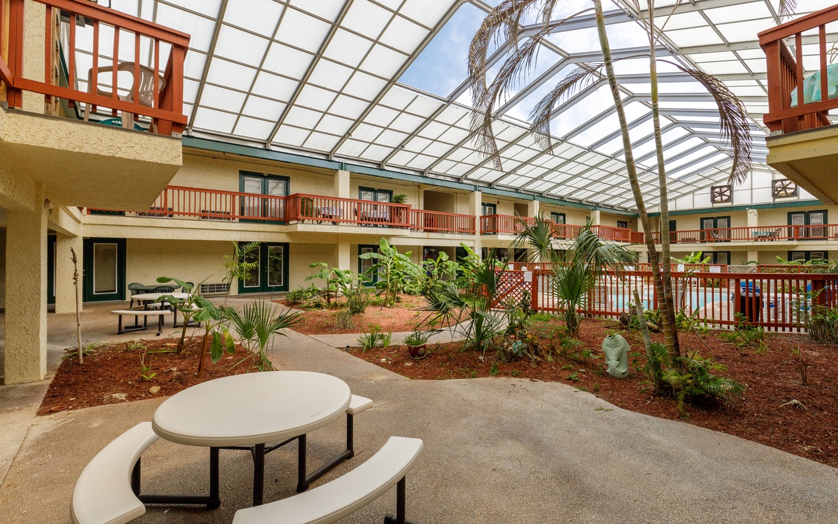 A stunning glass-covered courtyard creates your own tropical oasis with lush palms and peaceful seating areas.