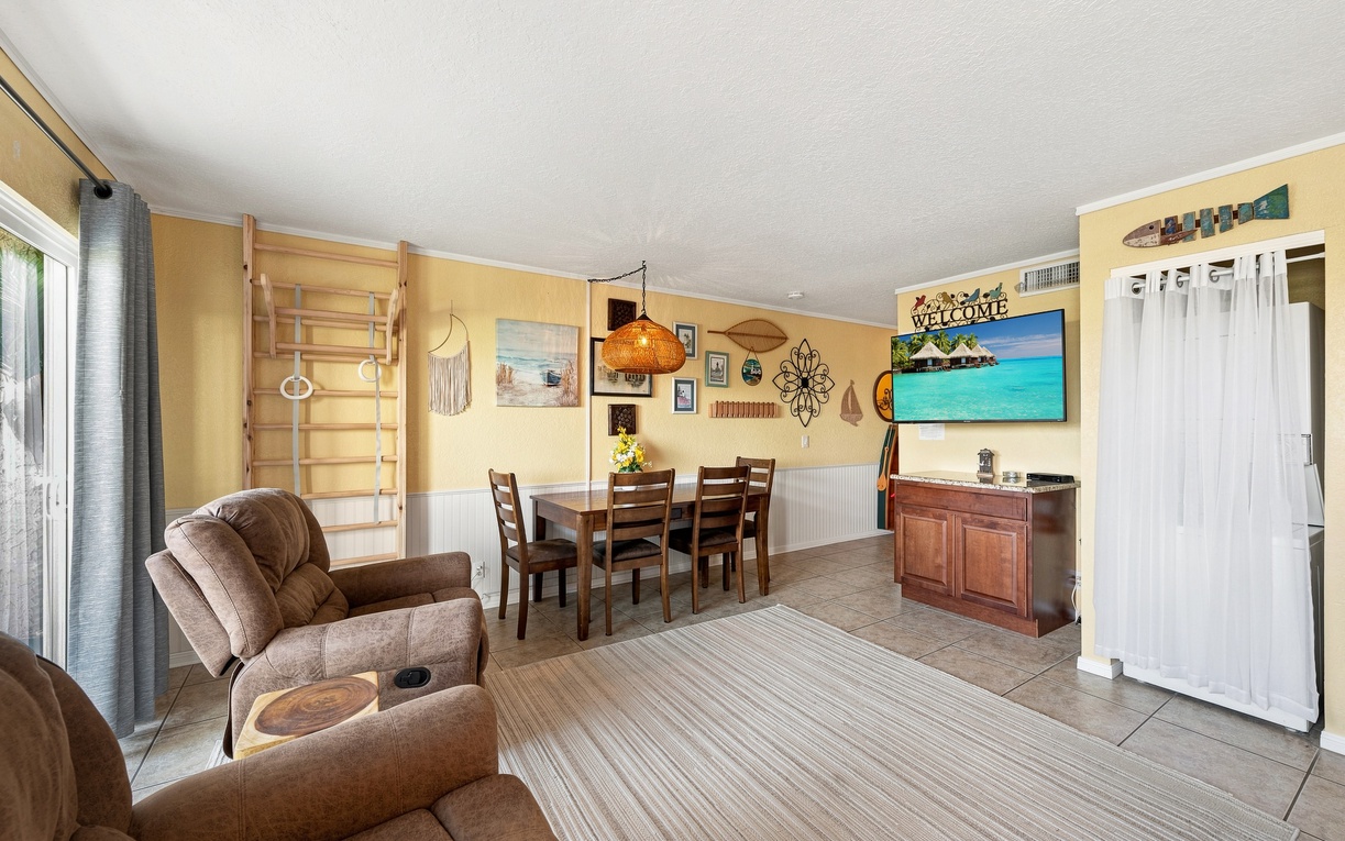 A bright, cheerful living and dining space invites you to relax in comfortable armchairs or gather around the dining table—your beachside home away from home with all the warmth and ease you deserve.