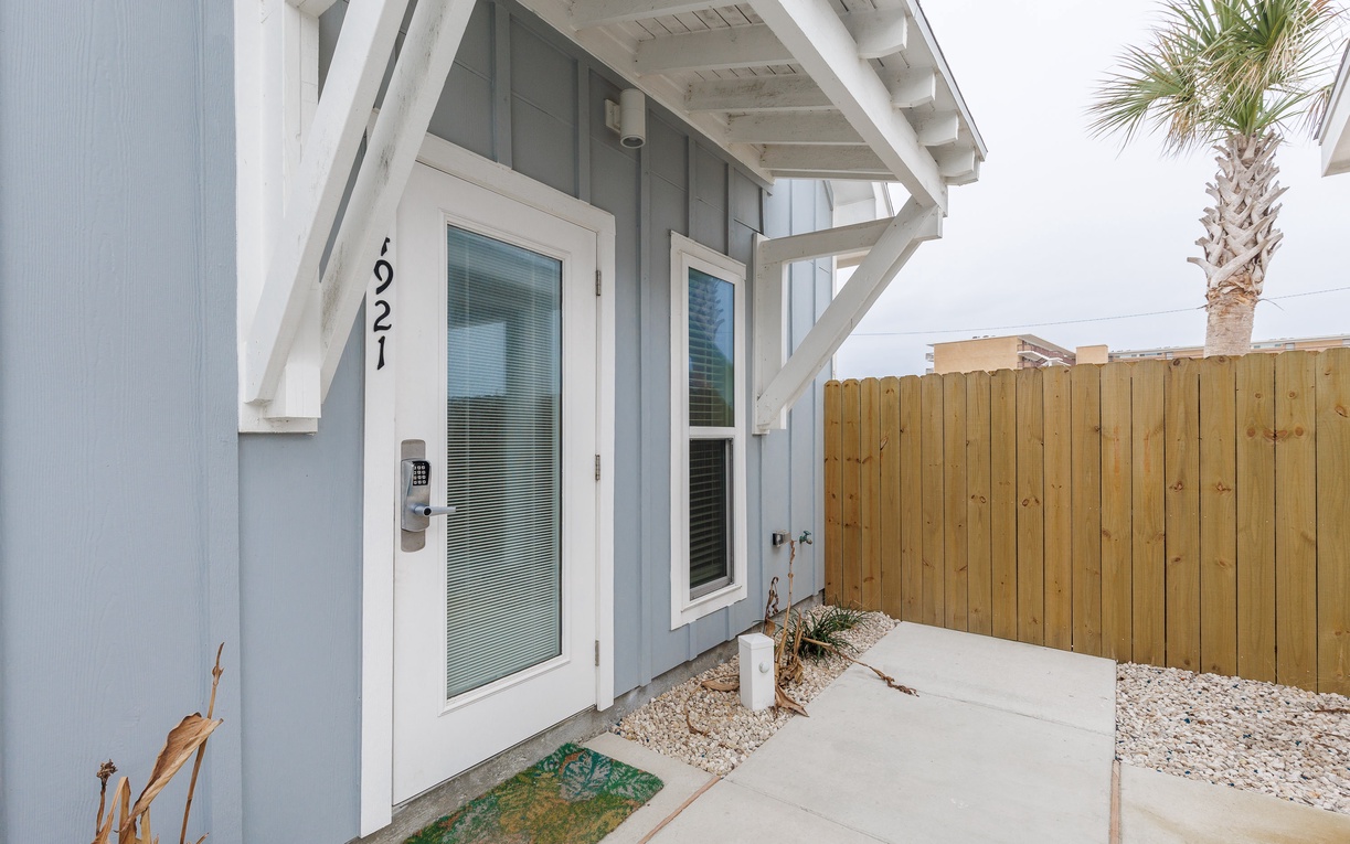 Modern coastal entrance with private patio and tropical palm tree creates your perfect beach getaway welcome.