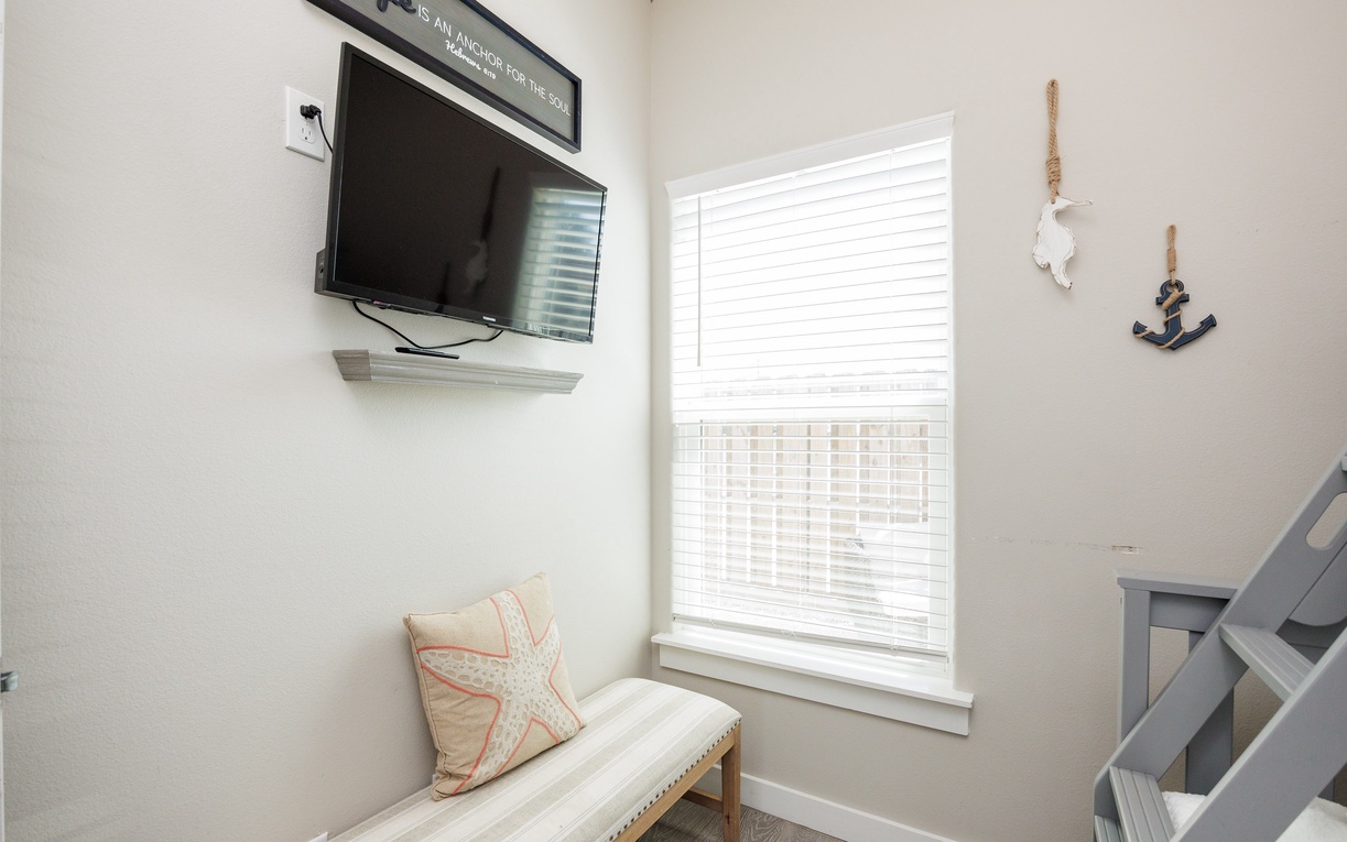 Relax in your cozy corner seating nook with a flat-screen TV and coastal decor, perfect for unwinding after beach adventures.