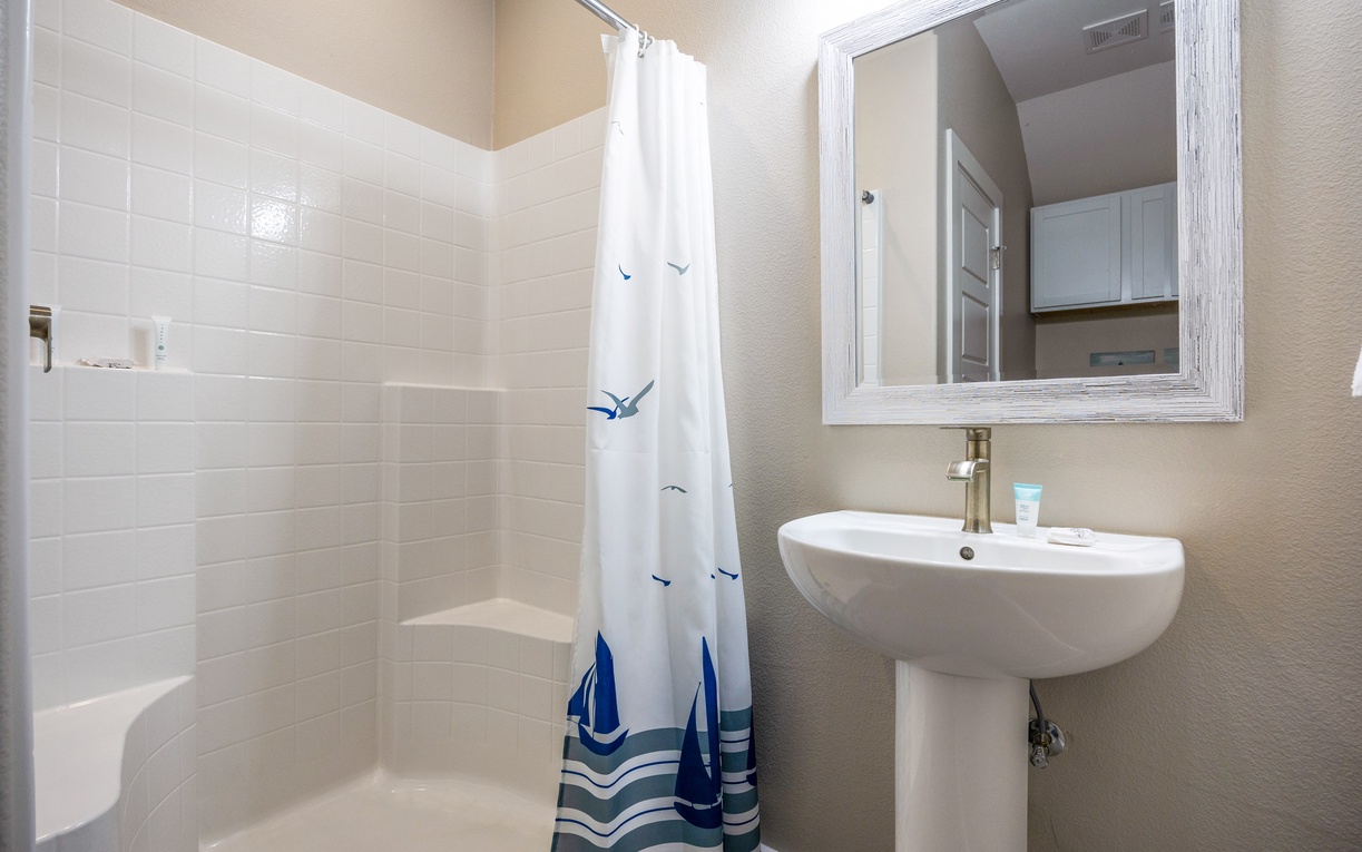 Step into your bright, well-appointed bathroom featuring a relaxing tub-shower combo and charming nautical touches that make you feel right at home.