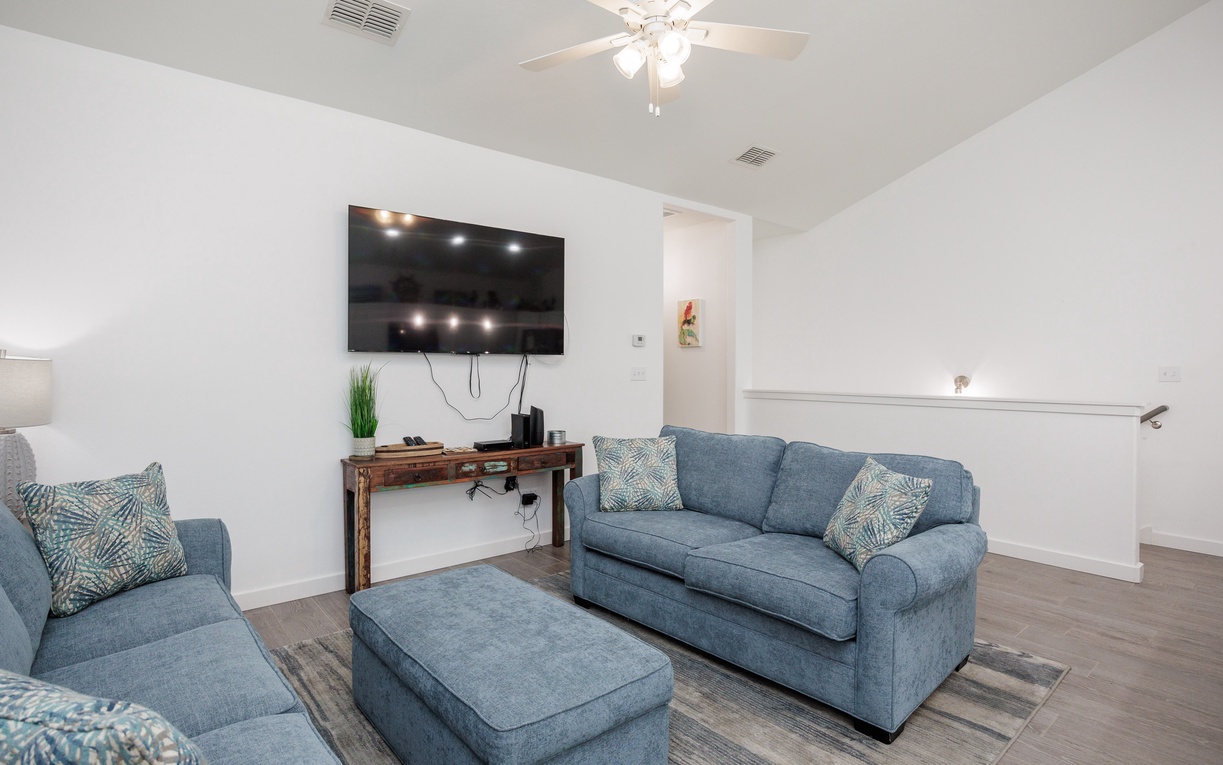 Unwind in your spacious living room with plush blue seating and large flat-screen TV for cozy movie nights.