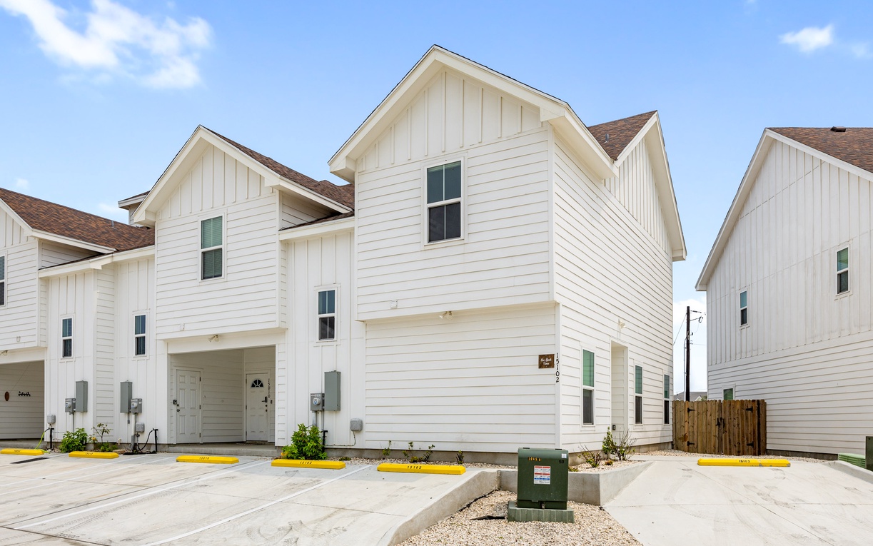 Modern white townhomes with clean lines and spacious driveways in a newly developed residential community.