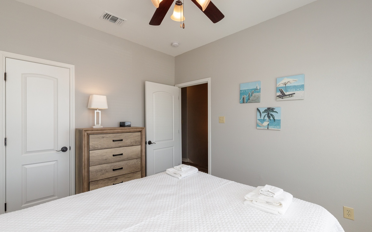 Drift off to peaceful sleep in your serene bedroom, where coastal artwork and gentle ceiling fan create the perfect retreat.