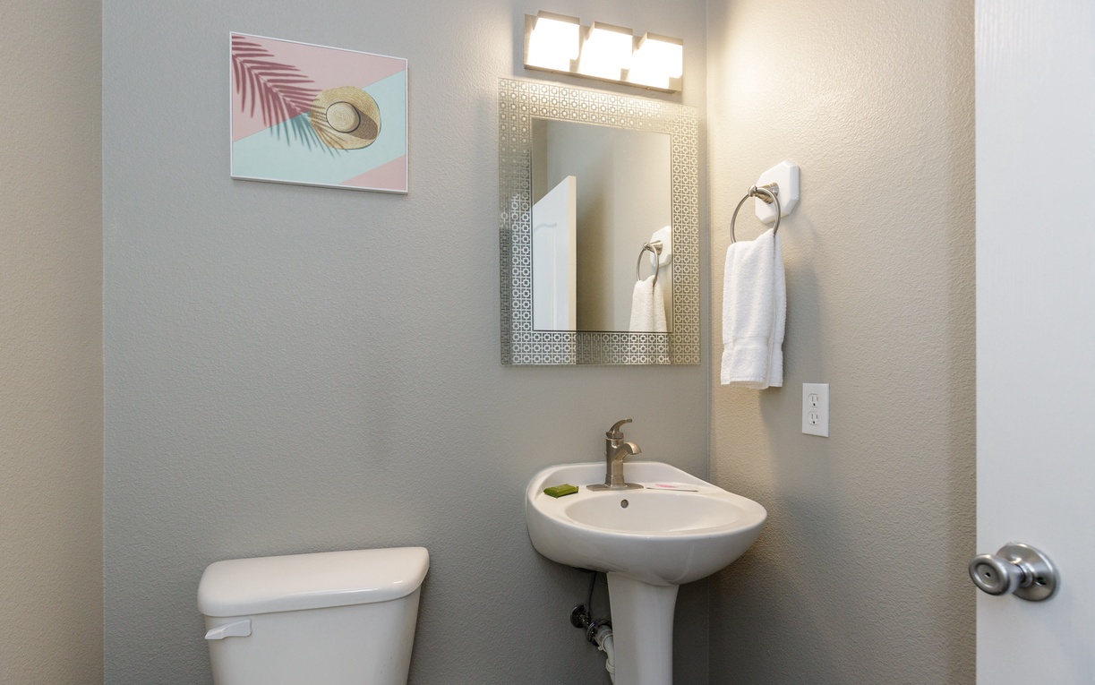 Your private half-bath features coastal artwork and fresh towels, creating a welcoming space for your convenience.