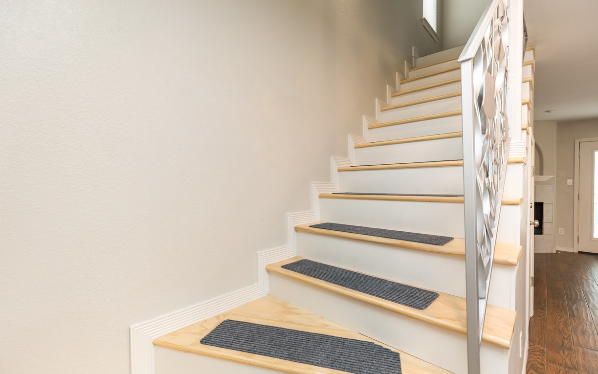 Ascend the beautiful wooden staircase with slip-resistant treads, featuring elegant white railings that guide you to your upper-level retreat.