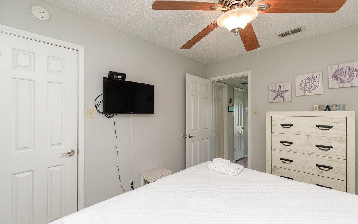 Relax in your peaceful bedroom with crisp linens, coastal artwork, and a ceiling fan to keep you comfortable all night long.