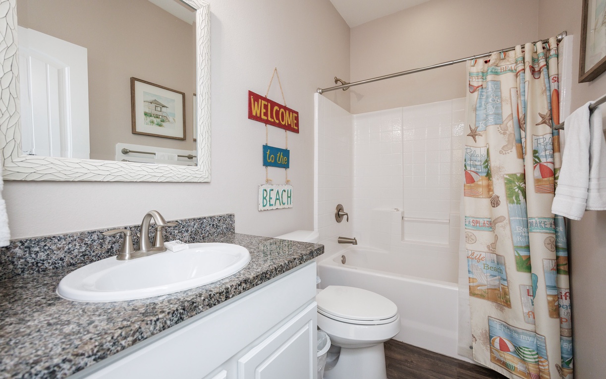 Your beach-themed bathroom welcomes you with cheerful coastal touches and a relaxing tub-shower combo for unwinding after your day.