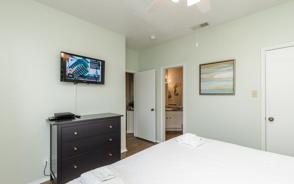 Unwind in your peaceful bedroom featuring crisp linens, entertainment setup, and an ensuite bathroom for ultimate comfort.