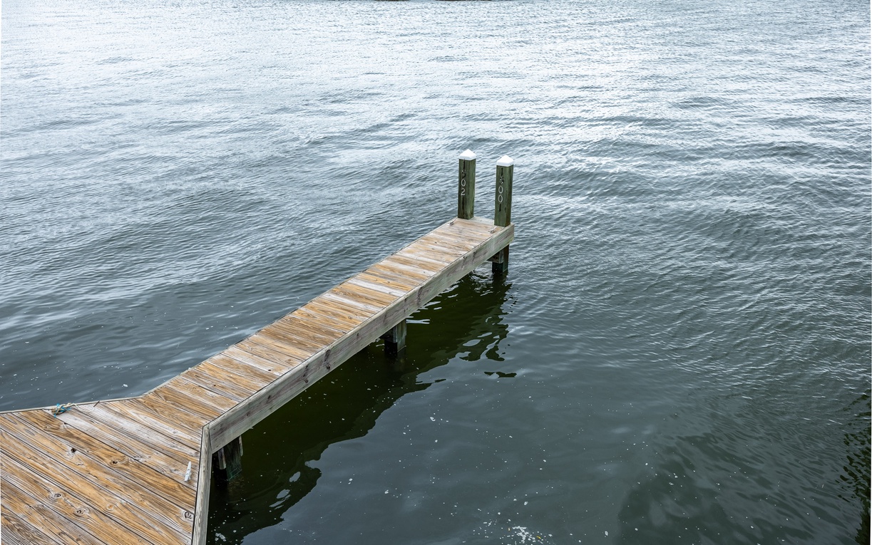 Wooden dock extending into calm lake waters, perfect for peaceful moments and water activities in the surrounding natural area.