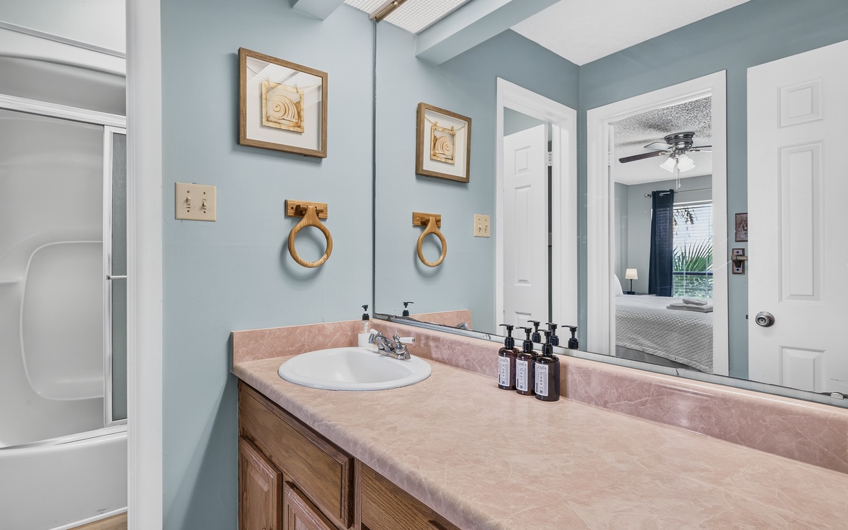 Step into your serene bathroom with calming blue walls, coastal touches, and a spacious vanity with premium amenities ready for you. The vaulted ceiling and natural light create a spa-like atmosphere where you can truly unwind.