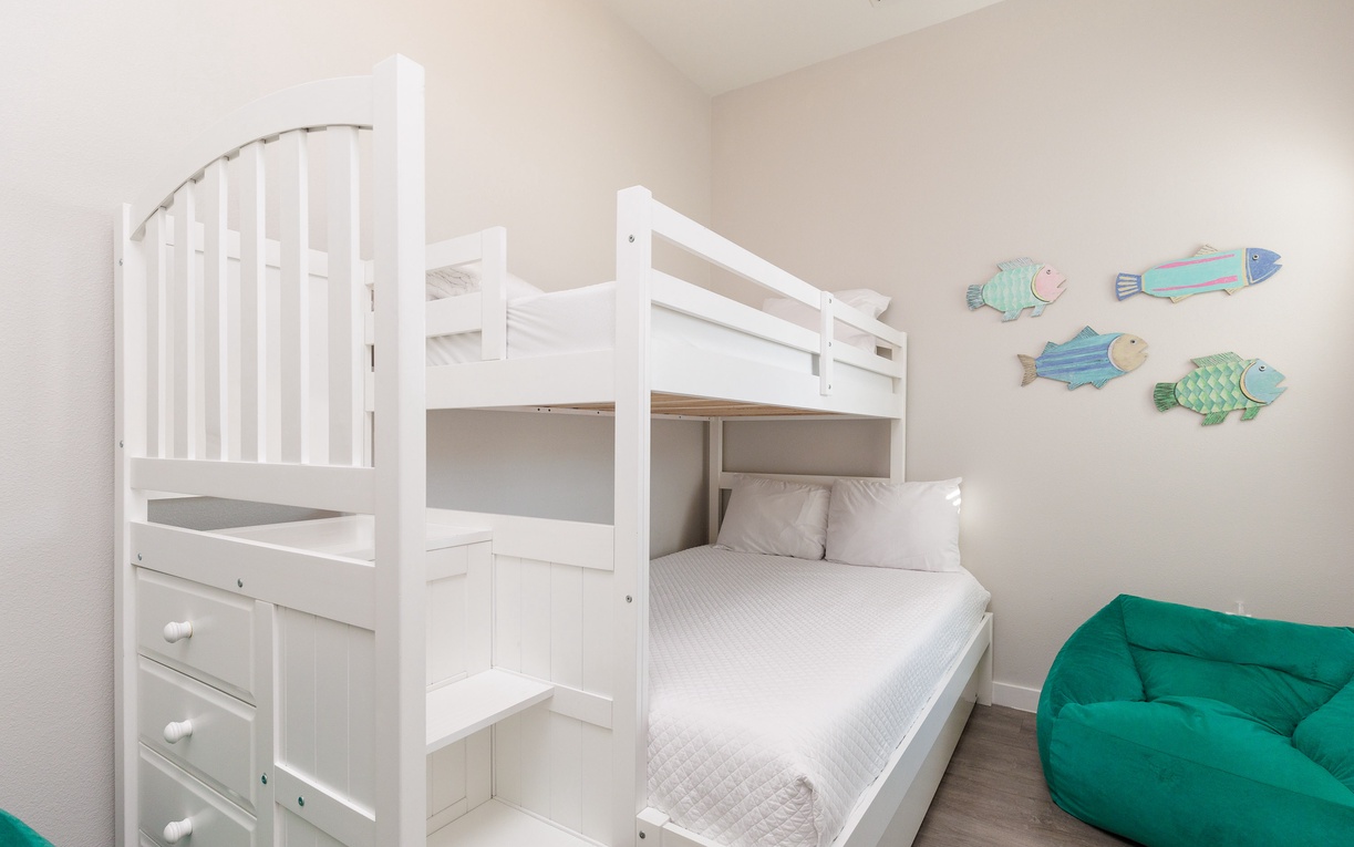 Your kids will love this playful bunk bed room with colorful fish wall art and a cozy bean bag for reading adventures.