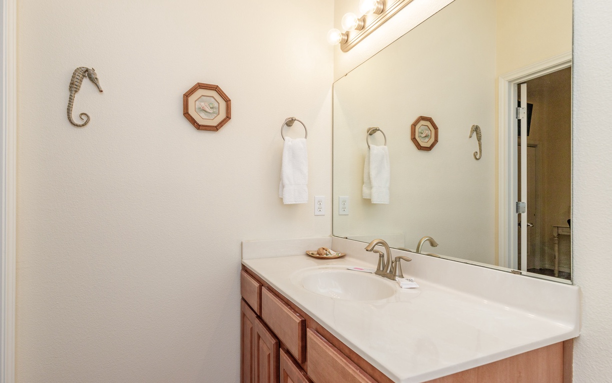 Freshen up in your coastal-themed bathroom with nautical touches, plush towels, and warm lighting creating a relaxing seaside retreat.