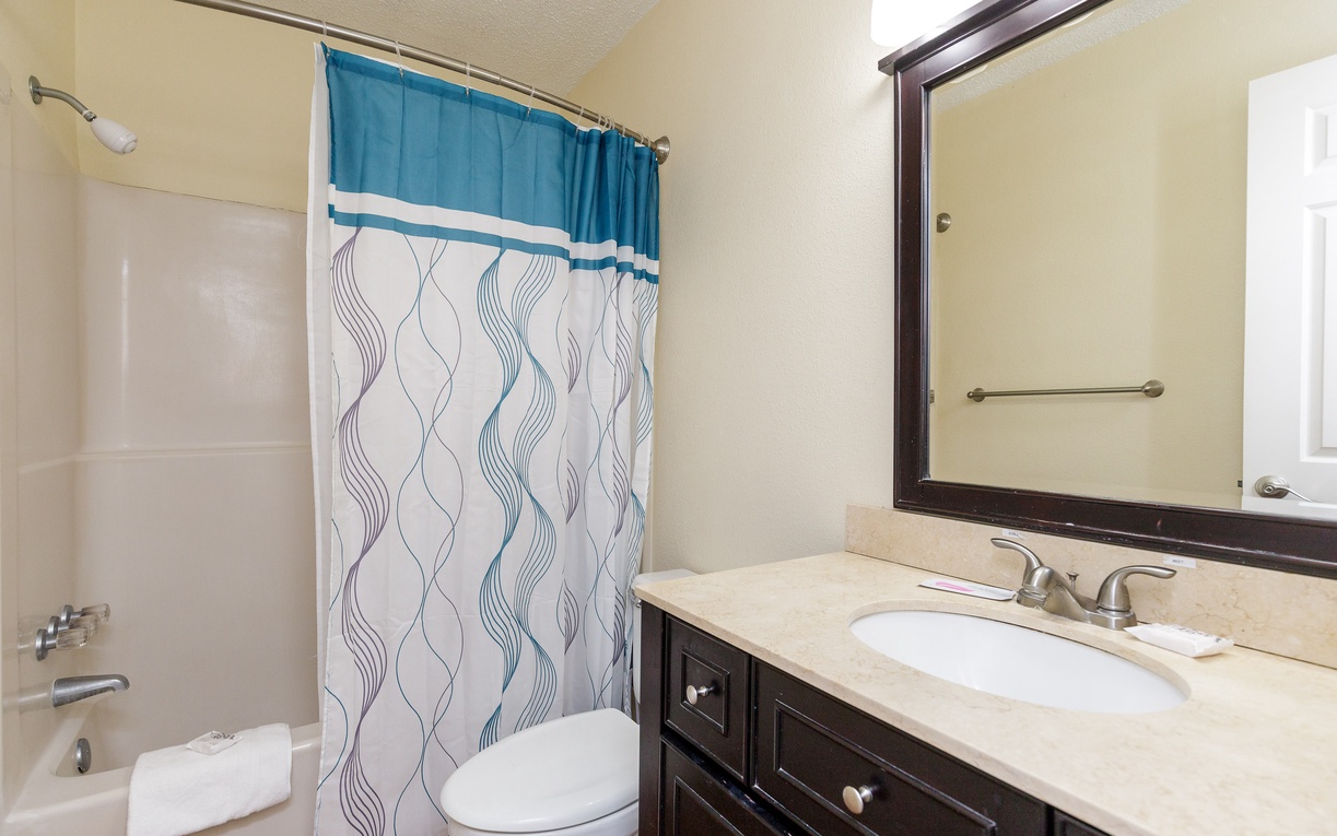 Your private bathroom features a spacious tub-shower combo, elegant vanity, and fresh towels waiting for your arrival.